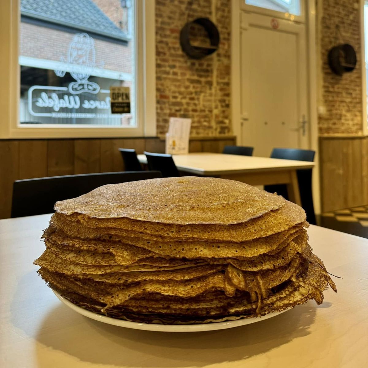 Een stapel vers gebakken pannenkoeken van Marcs Wafels met ons prachtig interieur van het wafel-pannenkoeken en ijssalon als achtergrond.